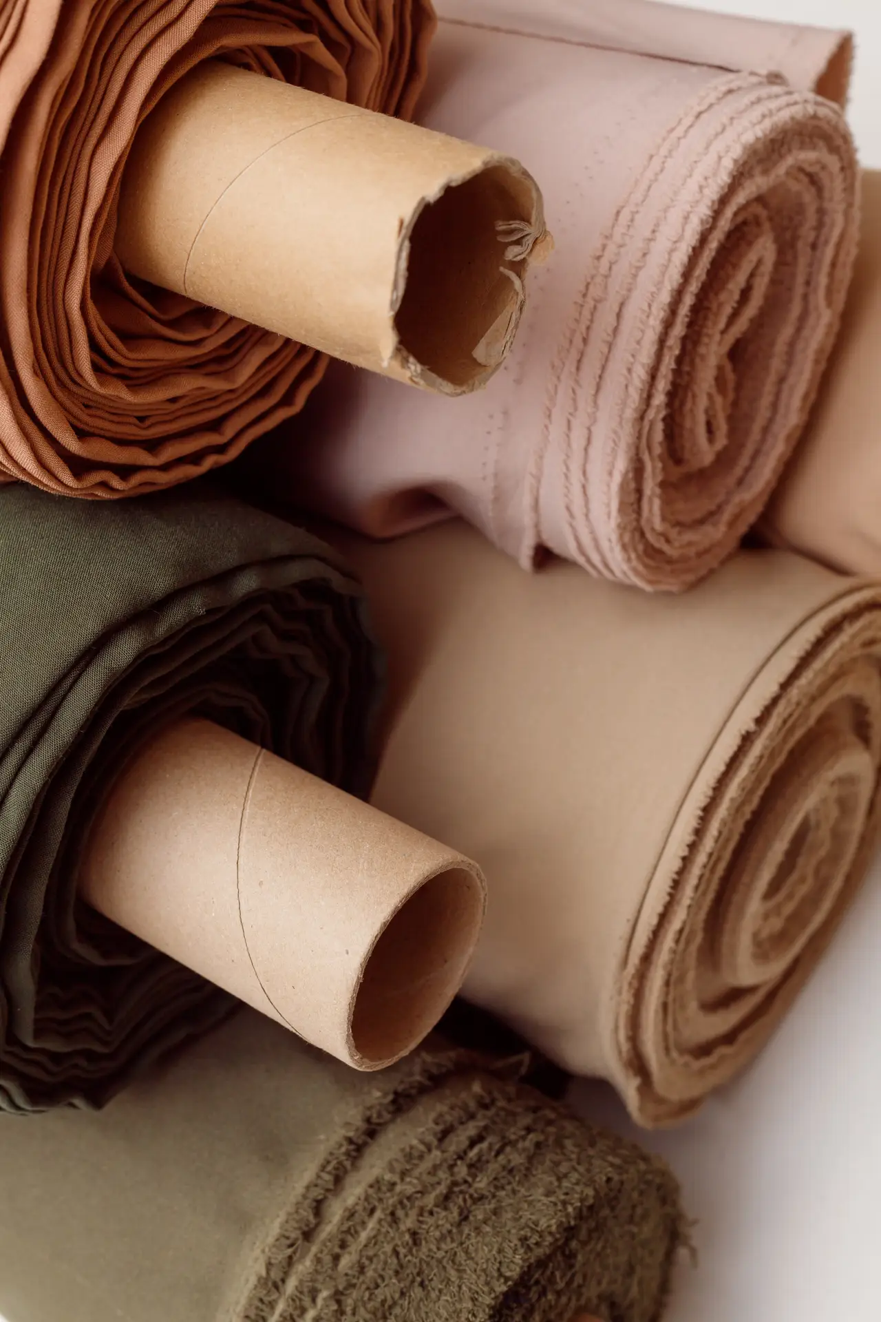 stack of pastel color fabric rolls of synthetic and natural fabrics