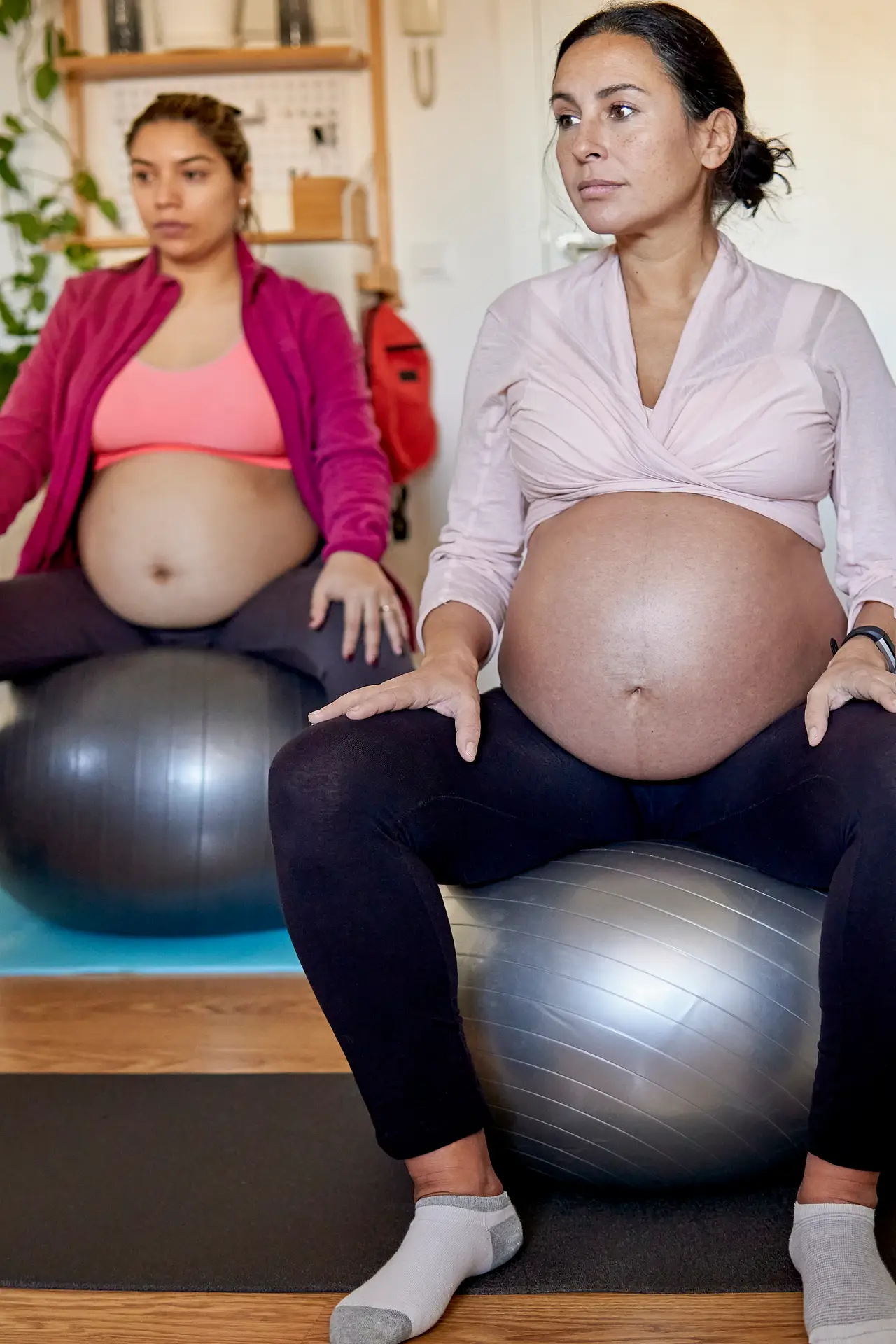 multiethnic pregnant women doing yoga at home using pilates balls